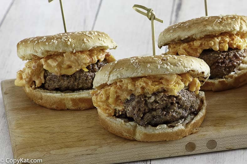 three pimento cheese burgers on a wood platter