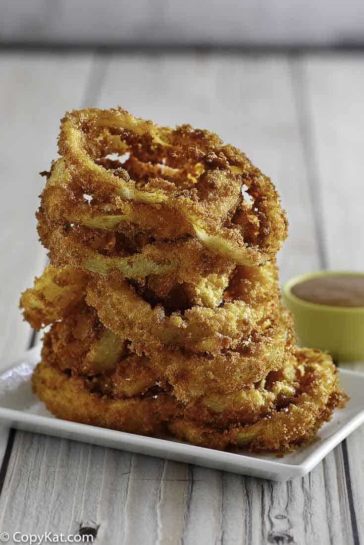 Homemade copycat Red Robin Onion Rings stacked on a white plate.