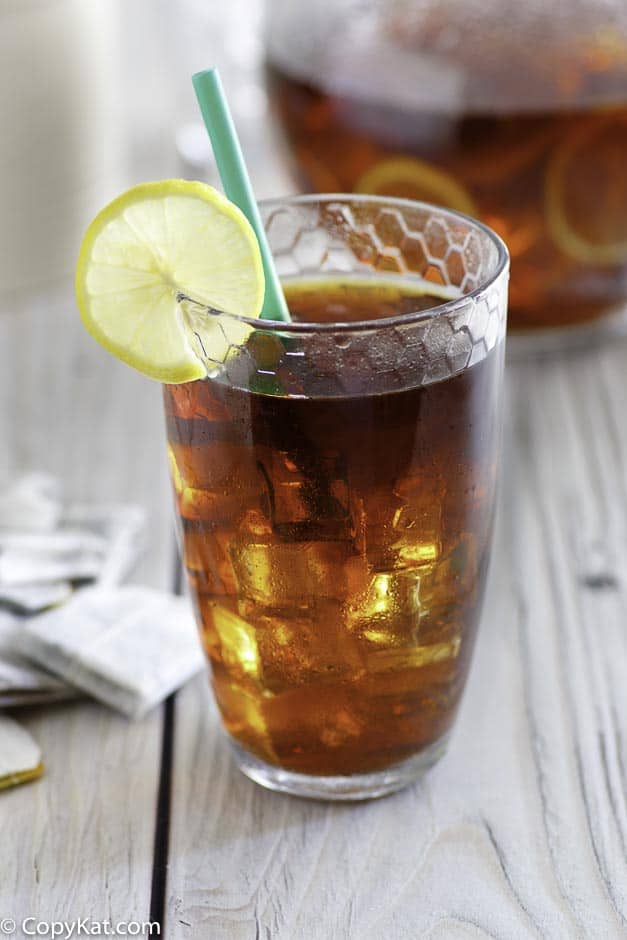 Homemade copycat McDonald's sweet tea in a glass in front of a pitcher of iced tea.