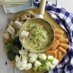 Cheese fondue with bread cubes, carrots, cauliflower, and more.