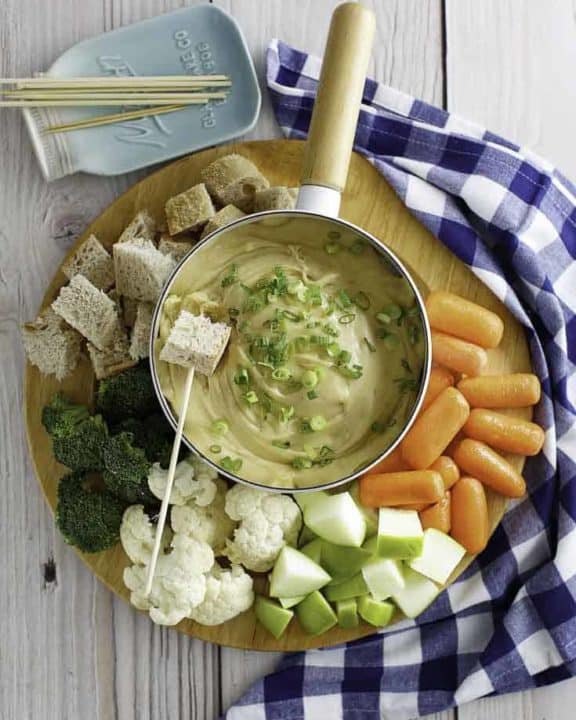 Cheese fondue with bread cubes, carrots, cauliflower, and more.