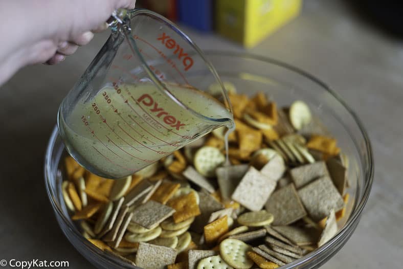 Pouring a seasoning sauce over crackers to make them taste great. 