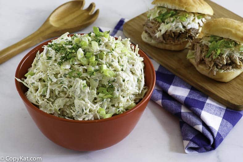 A bowl of homemade Houston's coleslaw next to pulled pork sandwiches