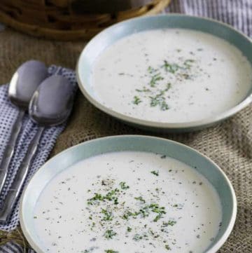 Two bowls of homemade potato soup with dried herbs sprinkled on top.