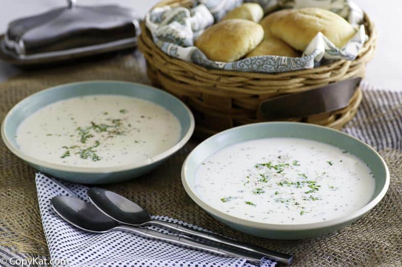 Two bowls of potato soup made from scratch served with hot rolls.