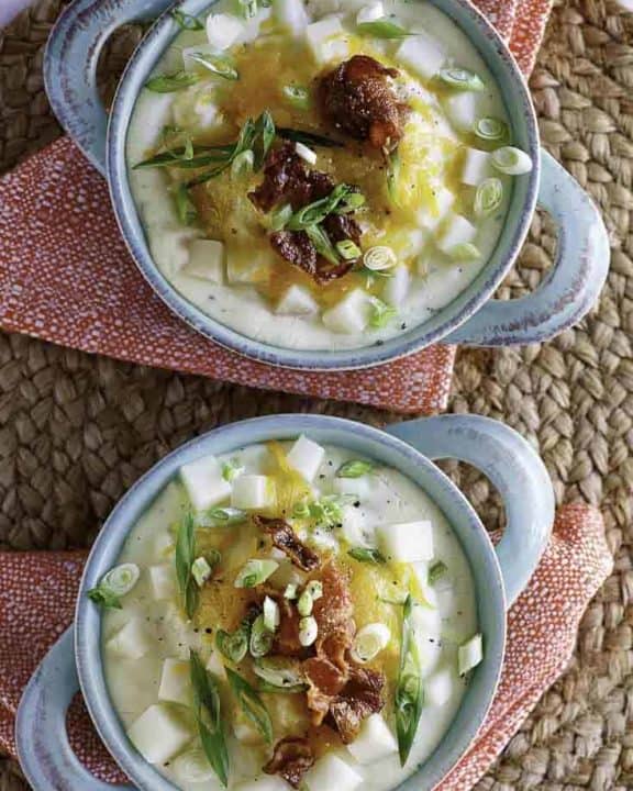 two bowls of baked potato soup with toppings of cheese and bacon