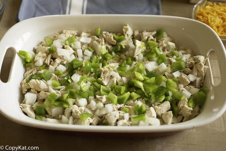 Cooked chicken is topped with chopped onions and green bell peppers.