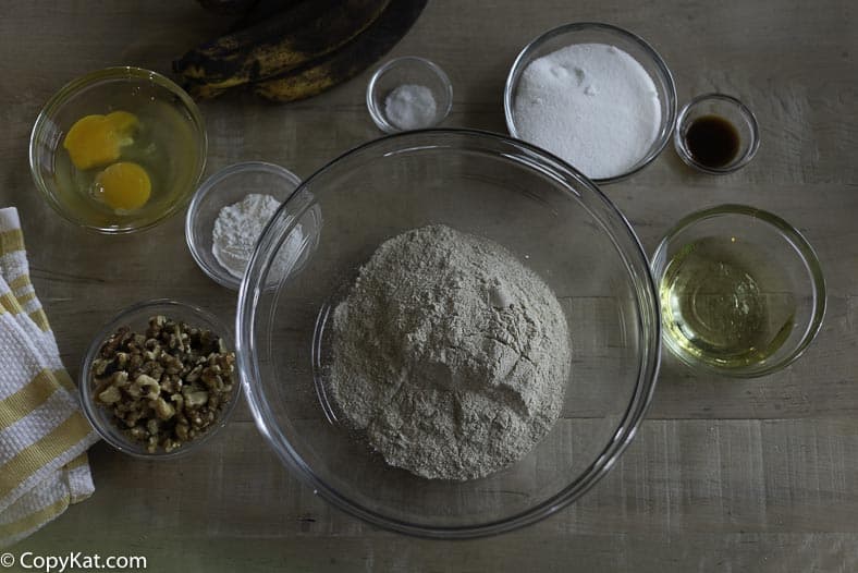 Ingredients for Whole Wheat Banana Nut Bread, bowl of whole wheat flour, sugar, bananas, nuts, and more. 