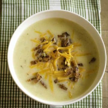 A bowl of creamy country potato soup topped with crispy bacon and shredded Cheddar cheese.