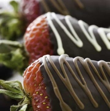 Three chocolate covered strawberries on a plate.