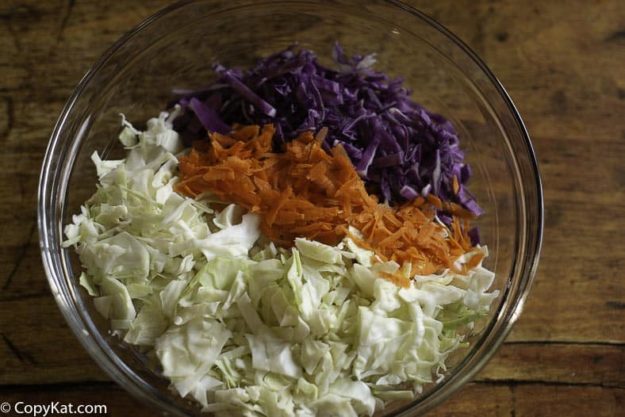 A bowl of shredded green cabbage, red cabbage, and shredded carrots. 