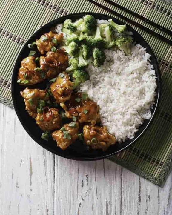 A plate of General Tso's chicken with rice and broccoli.