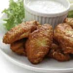 Homemade Junior's Buffalo wings and blue cheese salad dressing on a plate