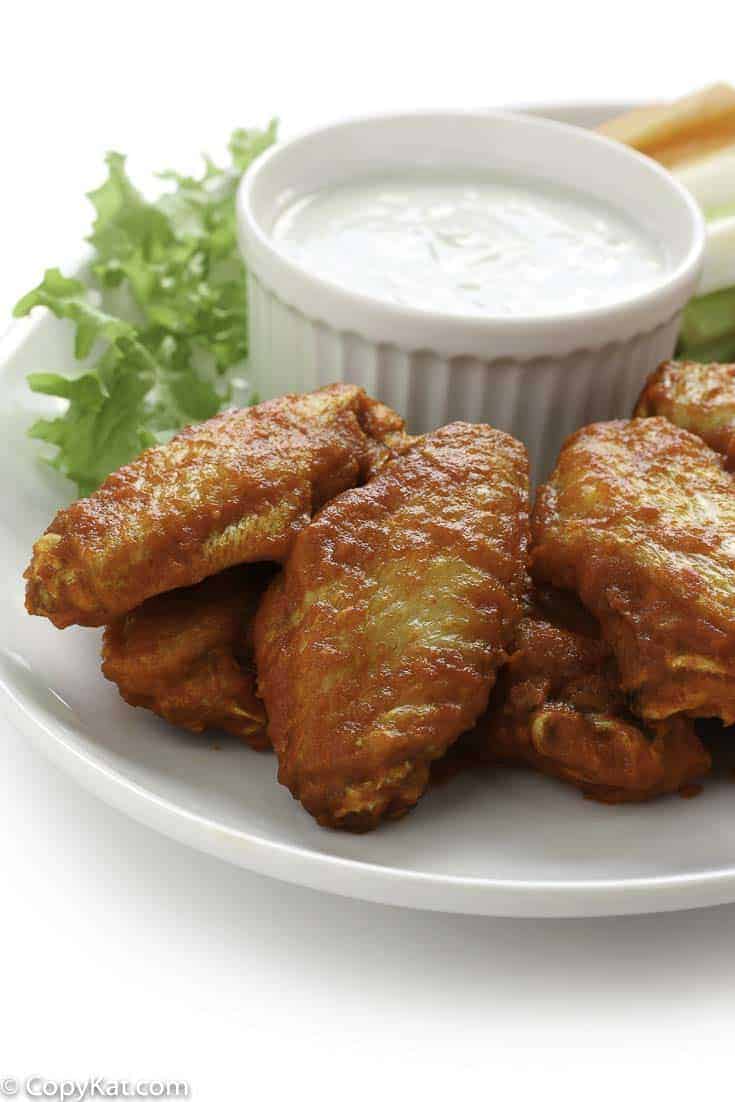 Homemade Junior's Buffalo wings and blue cheese salad dressing on a plate