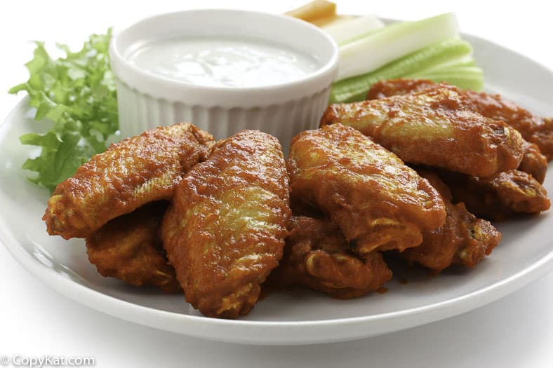 Homemade Junior's buffalo wings, celery sticks, and blue cheese salad dressings on a plate