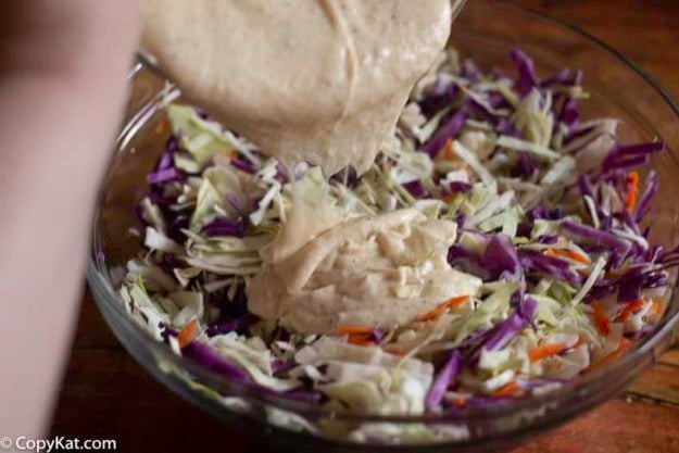 Pouring coleslaw dressing on shredded cabbage