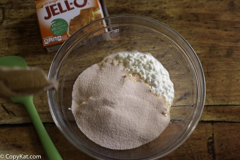 mixing together orange jello and cottage cheese when making orange fluff jello salad