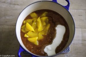 A jar of salsa, a can of peaches, and sugar in a pot.