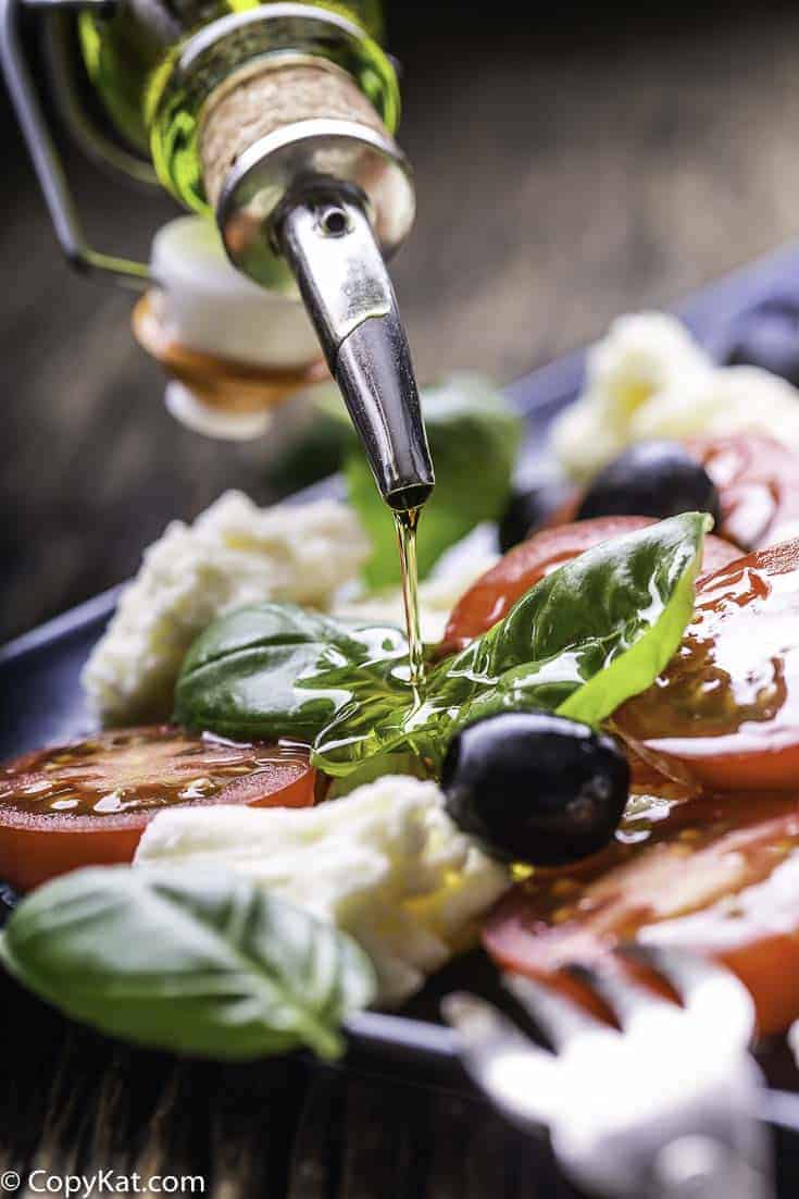 A plate of fresh mozzarella, tomatoes, basil leaves, and olive oil