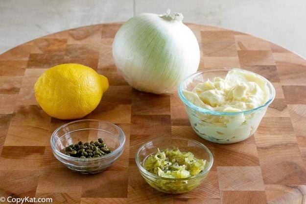 Ingredients to make homemade tartar sauce: mayonnaise, dill pickles, capers, lemon, and onion.