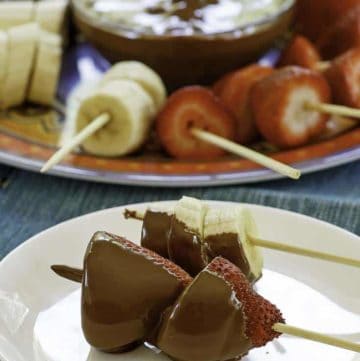 Chocolate fondue being served with bananas, strawberries, brownies and more.