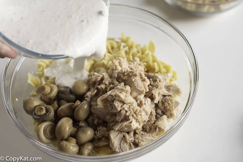 mixing together mushroom sauce, noodles, mushrooms, and tuna