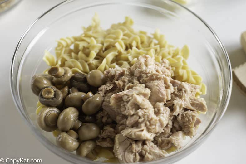 A bowl of extra wide egg noodles, canned tuna, and mushrooms