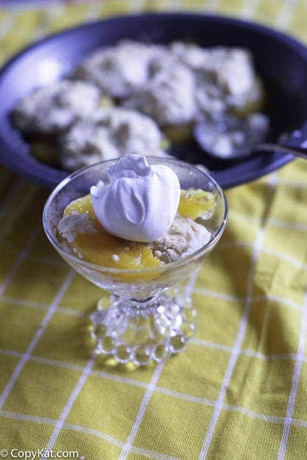 A glass dish with homemade peach cobbler and whipped topping