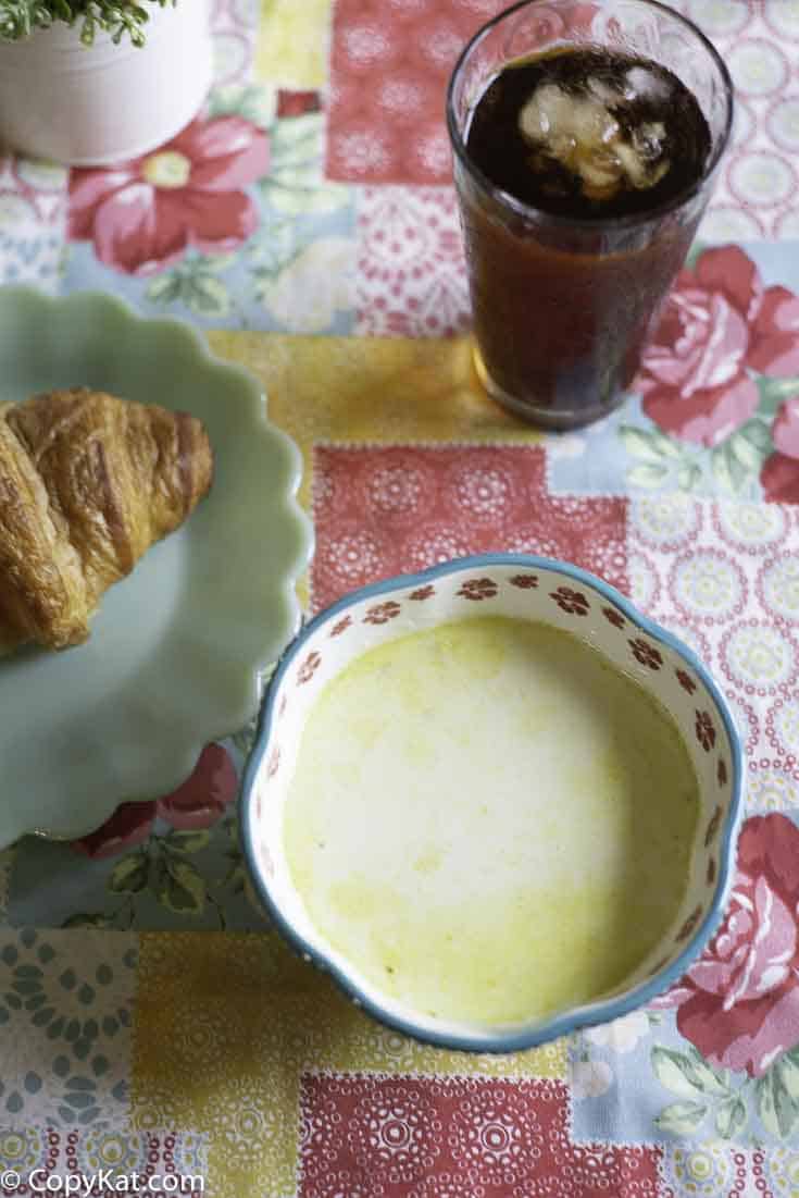 A bowl of homemade Dixie Stampede Cream of vegetable soup and a croissant.