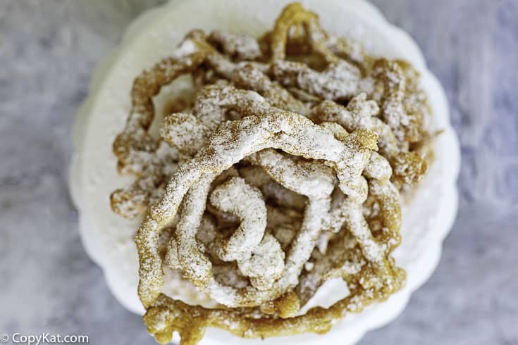 crispy homemade funnel cakes on a plate with powder sugar