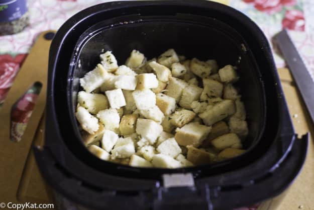 Uncooked croutons in an air fryer basket