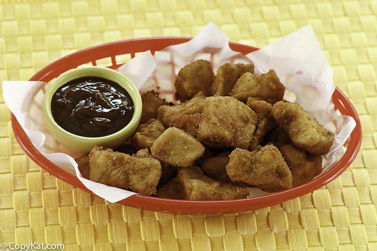 Homemade copycat Chick Fil A chicken nuggets and barbecue sauce in a red basket.