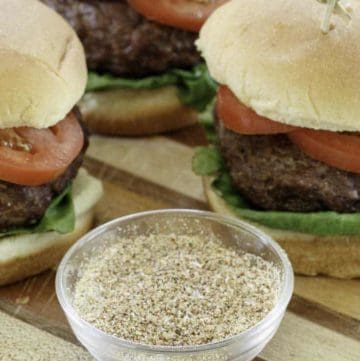 homemade burger seasoning and hamburgers on a wood cutting board.