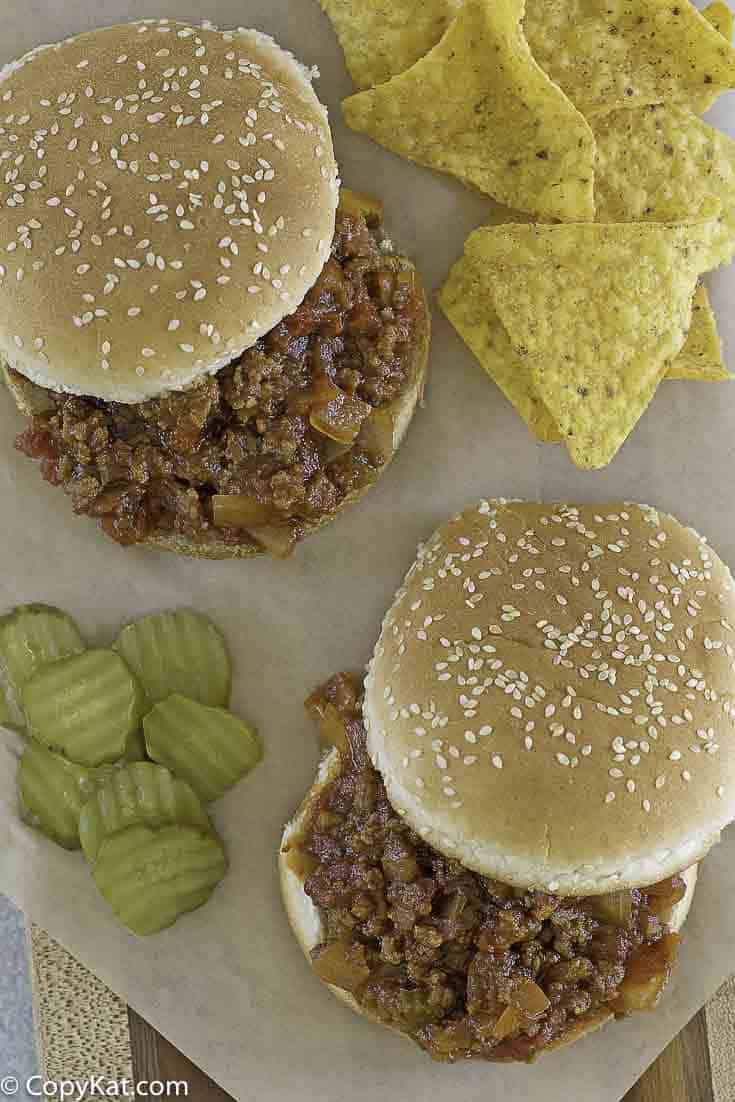 homemade sloppy joes on a plate with pickles and corn chips