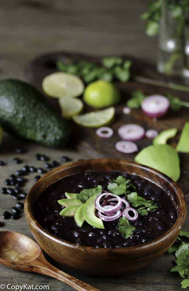 a bowl of cooked black beans with cilantro, lime, red onion and avocado. 