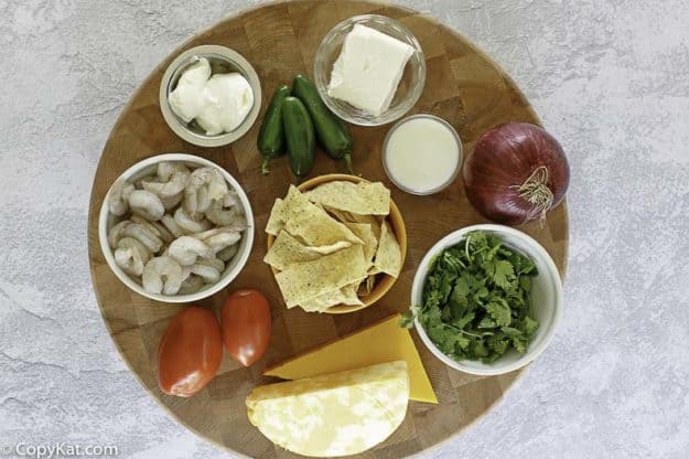 shrimp, cheese, cilantro, sour cream, corn chips on a board to make shrimp nachos