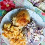 Baked chicken, cole slaw, and macaroni and cheese on a plate