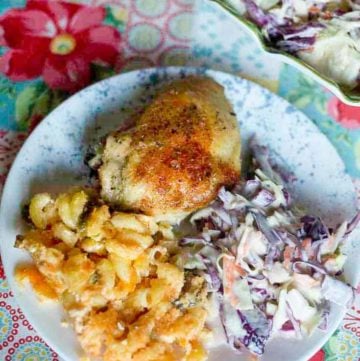 Baked chicken, cole slaw, and macaroni and cheese on a plate