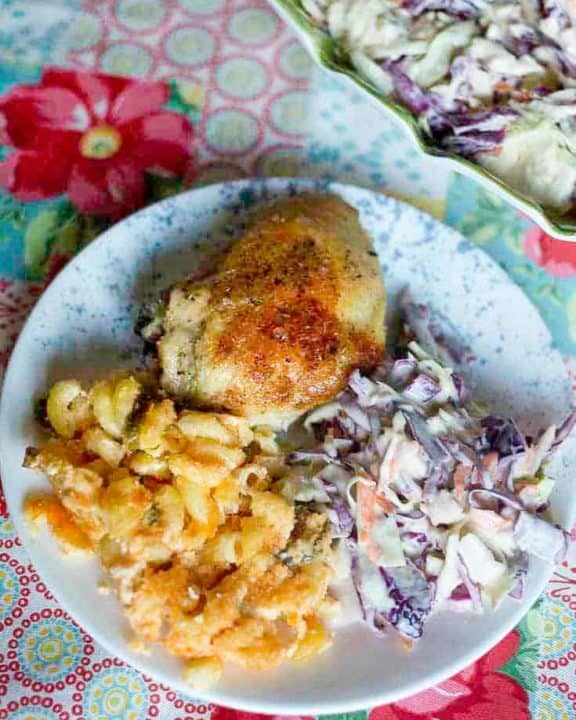 Baked chicken, cole slaw, and macaroni and cheese on a plate
