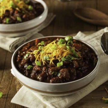 A bowl chili topped with cheese and green onions