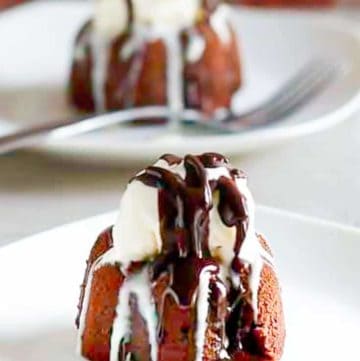 two triple chocolate meltdown cakes topped with ice cream and chocolate syrup