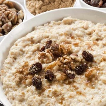 a bowl of oatmeal topped with raisins, walnuts, and brown sugar