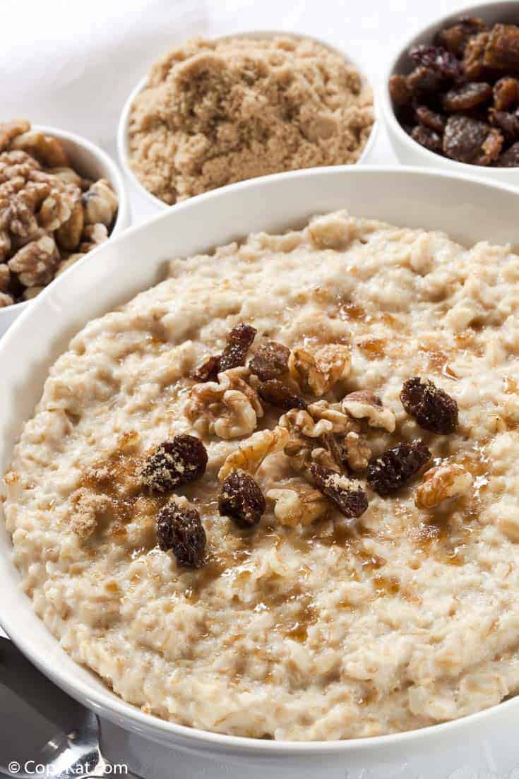 a bowl of oatmeal topped with raisins, walnuts, and brown sugar