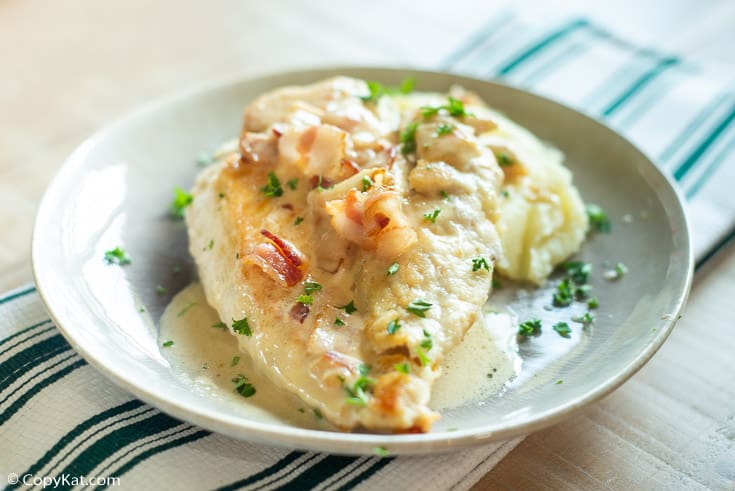 A plate of chicken marsala with bacon and mashed potatoes