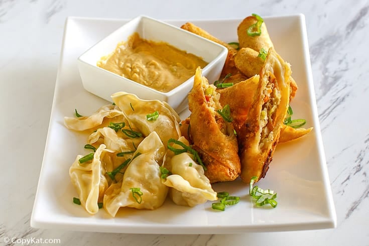 Chinese dumplings, egg rolls, and hot mustard on a white plate