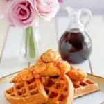 Homemade Grand Lux Cafe Chicken and Waffles served with a bottle of syrup