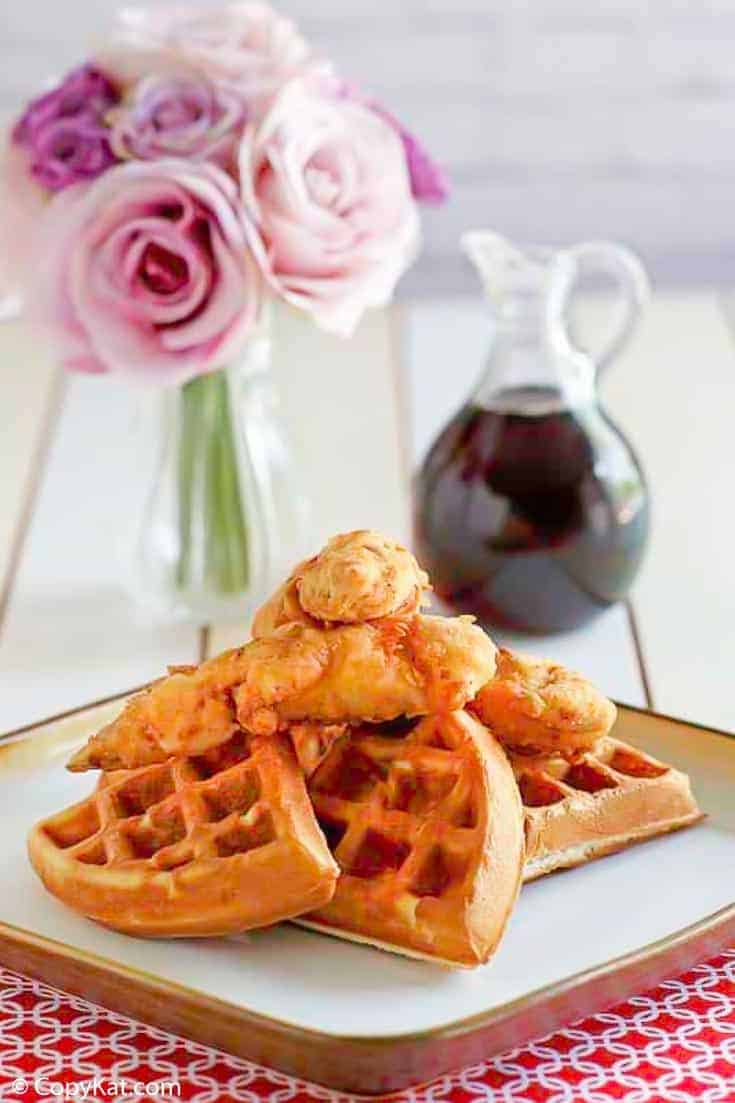 Homemade Grand Lux Cafe Chicken and Waffles served with a bottle of syrup