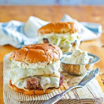 Two French onion burgers on a wood board