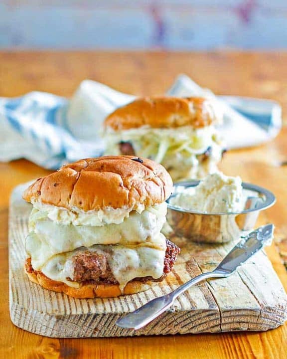 Two French onion burgers on a wood board