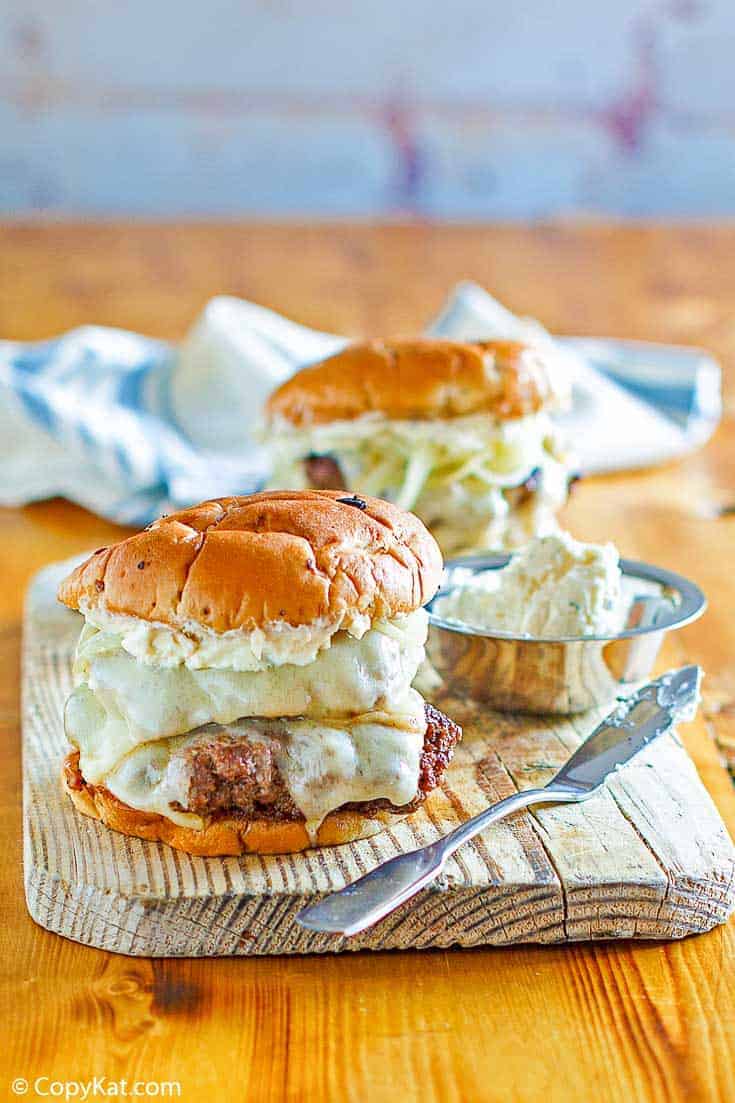 Two French onion burgers on a wood board